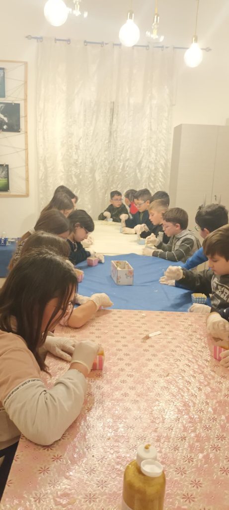 Il tavolo da lavoro con tutti i bambini intenti a decorare i saponi